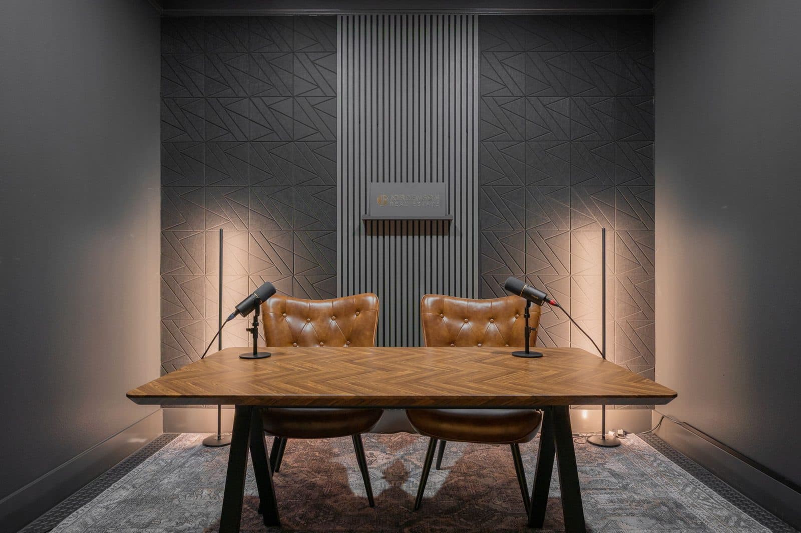 The JRE media studio with two chairs, microphones and a slatted acoustic wall